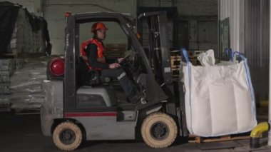 Palet yükleniyor, Forklift emniyeti, Depo navigasyonu. Depodaki işçiler paletleri taşımak için forklift yükleyicilerini özenle çalıştırıyorlar.