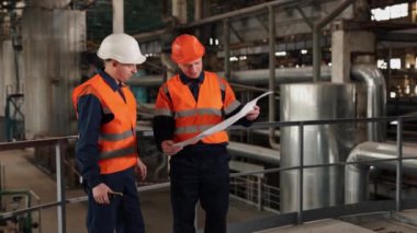 İnşaat çalışması, fabrika planı, proje tartışması. Bina planı, imalat alanında çalışan inşaat işçisi ve mühendisi tarafından inceleniyor..