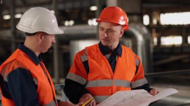İşçi incelemesi, üretim şemaları, makine çizimleri. Mühendis ve inşaatçılar için fabrika atmosferi tasarım çizimlerinin ortak çalışmasını ayarlar.