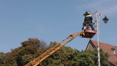 İşçi onarımı, metal direk, elektrik teknisyeni. Sokak lambası tamiri, tepedeki sokak lambasını tamir eden işçiler, yeni lamba montajı, elektrik direği tamir eden işçiler.