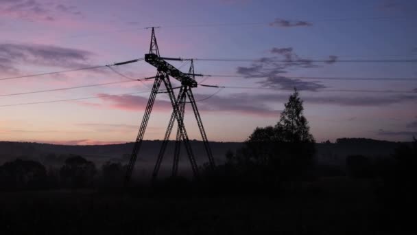 電圧塔 鋼鉄夜明け 夕暮れの空に身を包んだ鋼鉄ピロンは平野の上に織りなされ 風景を横断する電圧を示しました — ストック動画