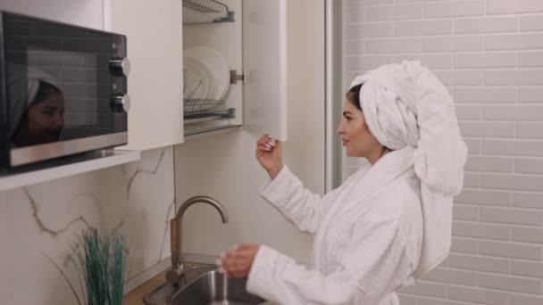 グラスウォーター 飲酒ルーチン モーニングシュート 健康的な食事 キッチンローブの女性はさわやかな飲み物のきれいな水にふさわしい — ストック動画