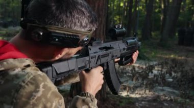 Periskop ayarlanmış, kamufle edilmiş asker, odaklanmış asker. Kamuflaj kıyafeti giymiş odaklanmış lazer savaşçısı, yoğun orman ortamında askeri hassasiyeti vurgulayan modern bir tüfekle nişan alıyor.