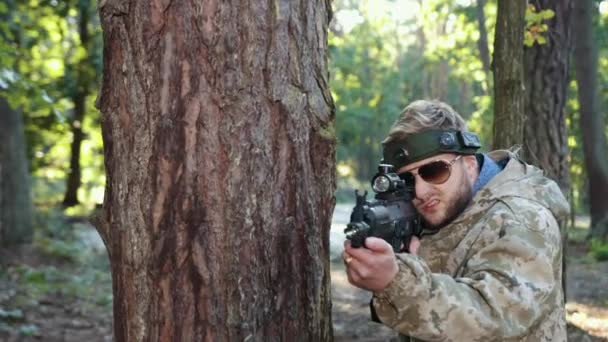 军事精准 标签射击 自然设置 在森林环境中 身穿迷彩服 头上有标记的人将自己固定在树上 瞄准激光标枪 向敌人射击 — 图库视频影像