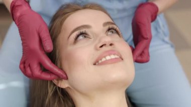 Ortodontik değerlendirme, kadın hasta, çene eklemi. Kadın hastaların çene eklemleri ortodontist-gnatholog tarafından elle yoklanıyor.