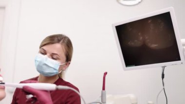 Diş taraması, doktor muayenesi, dişçi kadın. Genç kadınların ağız boşluğu, diş hekimi tarafından, intraoral kameranın yardımıyla kapsamlı bir muayeneden geçiriliyor..