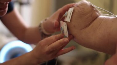 Fizik tedavi, rehabilitasyon, kas tedavisi. Erkek hasta, yüksek teknolojili tıp ortamında özenli terapist tarafından uygulanan elektroterapi elektrotlarıyla kas rehabilitasyonuna uğrar..