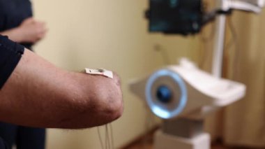 Ekte elektrotlar, terapi elektrotları, elektrot ayrıntıları. Hasta kolunun detaylı görüntüsü elektroterapi elektrotlarının yerinde olduğunu gösteriyor. Bu da rehabilitasyonda kullanılan nazik kas uyarma metodunu gösteriyor..
