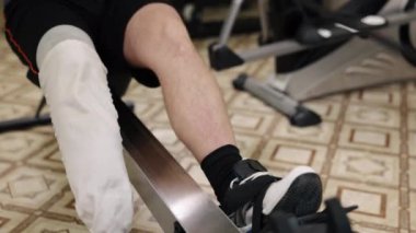 Özürlü insanlar, kol ve bacak egzersizleri, orta kürek çekenler. Protez bacak kullanan adam fitness kulübünde kürek çekme makinesinde egzersiz yapıyor..