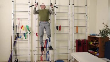 Protez egzersiz, uzuv gücü, terapi rutini. İnsan Protez Bacağı, yapay kol terapi odasındaki parmaklıklar üzerinde rehabilitasyon ekipmanıyla barfiks egzersizleri yapıyor..