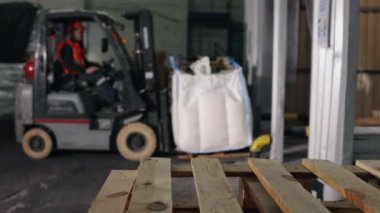 Depo lojistiği, depolama çözümleri, operasyon verimliliği. Depo çalışanı tarafından yönetilen forklift yükleyicisi, depolama tesisinde paletleri taşımakla meşgul..