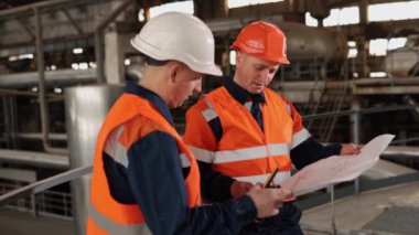 İşçi geribildirimi, işçi incelemesi, planlar. Fabrika sınırları içinde, mühendis ve inşaat uzmanı tasarımların karmaşıklığını araştırıyor.