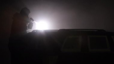 Otomotiv boyası, ilkel uygulama, doku efektleri. Sprey boyayla araba boyarken gölgeli şahıslar, puslu sahne ile çelişen arka plan ışığı sayesinde gölgeleniyor..