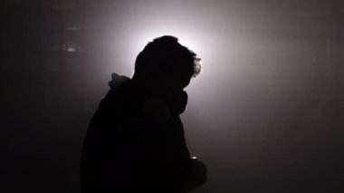 Dekoratör resmi, boya sisi, çevre aydınlatması. Sise sarılı atölyede, zanaatkar dikkatlice çalışır, koruyucu maskesi arka planda, sprey boyayla boyarken vurgulanır..