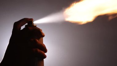Yangın güvenliği, koruyucu maske, sanat tehlikeleri. Karanlık ve puslu arka planda siluetler, güvenlik için maske takarak çarpıcı bir yangın patlaması yaratmak için aerosol kutusu kullanırlar..