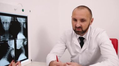 X-ray Açıklaması, Radyoloji Tartışması, Odaklanmış Doktor. Beyaz önlüklü kel erkek doktor, profesyonel olarak hastaya röntgen görüntülerini açıklar..