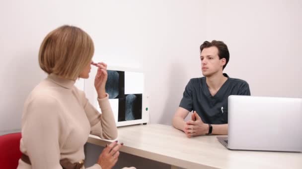X光分析 医疗办公室 健康建议 女病人在诊所与男医生讨论X光检查结果 — 图库视频影像