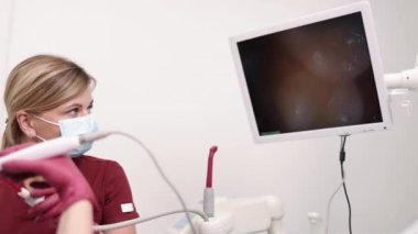 Diş kontrolü, ağız boşluğu, diş aletleri. Diş hekimliği uzmanı, genç bir kadının ağız boşluğunu incelemek için intraoral kamera kullanıyor..