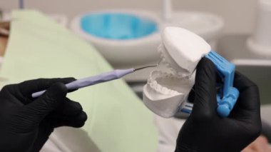Diş modeli, ofis aletleri, diş tedavisi. Yakın plan dişçiler, diş modelleri ve diş aletlerini tutan eldivenli kişilerdi.