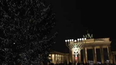 Brandenburg Kapısı, Dekoratif Işıklar, Berlin Noel. Brandenburg Kapısı 'nın yanında, ışıl ışıl bir Noel ağacı ve geceleri ışıl ışıl parlayan bir menorah..
