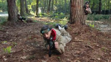 Eğik pozisyon, orman ortamı, eğitim ortamı. Kamuflaj kıyafetli lazer nişancı, ağaçlık alanda hassas görüşü olan paintball tabancasını titizlikle hedefliyor..