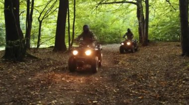 Farlar açık, gece gezintisi, ATV ormanı. Miğferli ve kamuflajlı, grup araçları orman yolunda yol alıyor, farları açıkken yol alıyorlar..