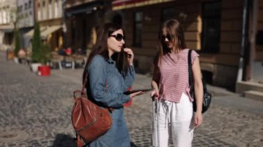 Elektronik seyahat, E-navigasyon, Turist Uygulamaları. İki kadın tatilci, yolculukta dijital evrimi gösteren tablet üzerinde kendi yollarını çiziyorlar..