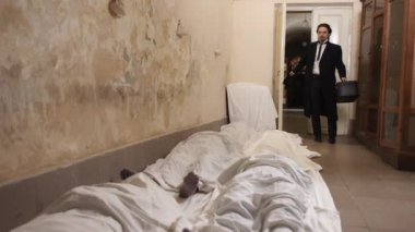 İnsan çok sayıda sivilin şokuna uğrar, ayaklar yere basar, cesetler çarşafla kaplanır. Rusya 'nın Ukrayna' daki saldırı savaşının kurbanları. Halkın soykırımı