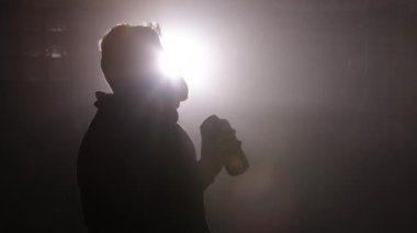 Boya spreyi, sisli ortam, koruyucu ekipman. Arka plan sisli atölye atmosferinde parlıyor, kendini adamış zanaatkârların koruyucu maskeli sprey boyalarını ışıklandırıyor..