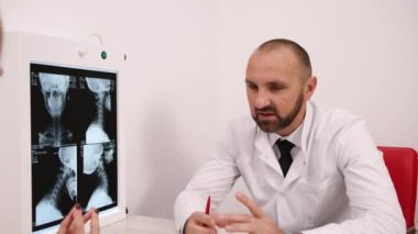 Kel Doktor, Sağlık Açıklaması, Tıbbi İnceleme. Beyaz önlüklü kel erkek doktor, röntgen görüntülerini hastaya, odaklanmış ve profesyonel.