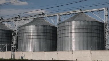 Temiz gökyüzü, demiryolu altyapısı, endüstriyel kurulum. Endüstriyel silolar beyaza boyanmış ve eşleşen binalar demiryolu kenarında, gökyüzünün altında tek bir bulut bile yok..