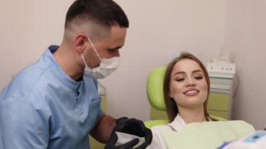 Ağız retraktörü, diş aletleri, diş muayenesi. Hasta dişçi koltuğunda oturuyor, mavi giyinmiş, ağız retraktörü kullanarak sözlü muayene yapıyor..