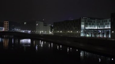 Berlin sahnesi, şehir yansımaları, Berlin gecesi. Gece Berlin 'de modern binalar sergileniyor. Nehre güzel yansıyan aydınlık cepheli binalar..