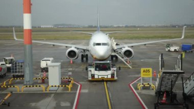 Cezalı uçak, bulutlu bir gün, terminal personeli. Bulutlu bir günde, uçak yer desteği ve çeşitli araçlarla kapıda duruyor..