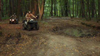 Grup gezisi, Woods navigasyon, ATV grubu. Kamuflaj kıyafetleri ve miğferleri olan grup insanlar orman yolunda ATV 'lere biniyor, farları açık halde ormanda geziniyorlar..