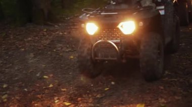 Off-road sürücüsü, ATV yolu, kamuflaj macerası. Yoğun ormanda, kamuflaj kıyafetli miğferli ATV sürücüsü toprak yolda, farları kullanarak etrafı kolaçan eder..