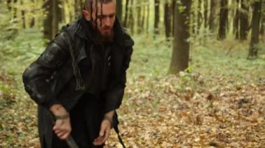Kuzeyli göçebe, Axe swing, sonbahar ortamı. Sakallı Viking koyu renk giysiler giyip sonbahar ağaçlarının arasında baltayla odun kesiyor..