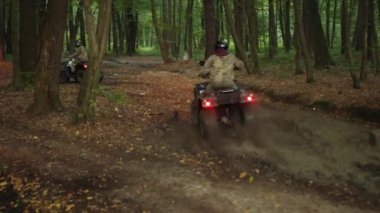 Grup şöförleri ATVler, Miğfer güvenliği, grup keşifleri. Grup miğferleri kamuflaj elbiseli bireyler orman yolu boyunca ATV 'lere biniyorlar, farları yol aydınlatıyor..