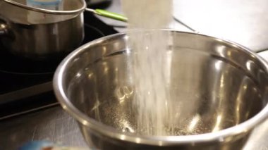 Doldurulmuş şeker, paslanmaz kase, karıştırma kabı. Parlak paslanmaz çelik karıştırma kabına şeker dökülen malzemelerin yakın plan çekimi, dökümü yakalama hareketi, yemek tarifi hazırlığı, karıştırma için metal kase.