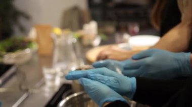 Mavi eldivenler, eldivenli eller, yemek güvenliği. Mutfak ortamında yemek, hassasiyet ve hijyen konularında mavi eldiven takan yakın çekim eller, güvenlik ve temizliği vurguladı..