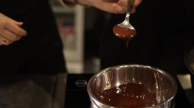 Erimiş çikolata, damlayan kaşık, çikolata akışı. Yakın plan çekimde kaşıktan damlayan yumuşak, erimiş çikolatadan paslanmaz çelik kaseye, tatlı yapımına, kaşıktan akan çikolataya, hazırlığa