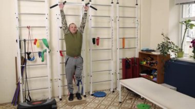 Fitness protezi, protez güç, iyileşme jimnastiği. Terapi seansında, yapay bacaklı bir adam duvar parmaklıkları üzerinde çalışır, vücudunun üst kısmına odaklanır..
