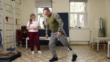 şınav terapisi, jimnastik terapisi, rehabilitasyon merkezi. Antrenör gözetiminde protez bacaklı bir adam rehabilitasyon merkezinde şınav egzersizi yapıyor..