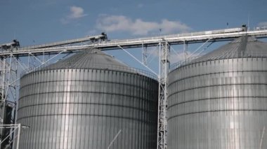 Dış bina, silo silo silindir, endüstriyel tasarım. Tahıl deposu için metalik silolar içeren endüstriyel kompleks parlak mavi gökyüzü tarafından çerçevelenir.