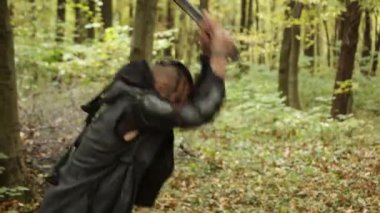 Viking savaşçısı, ağaç kesme, orman düzenlemesi. Sakallı ve koyu renk elbiseli Viking adam sonbahar ormanında baltayla odun kesiyor..
