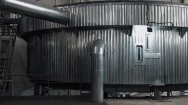 Metal tanklar, bira fabrikası boruları, bira fabrikası üretimi. Çağdaş endüstriyel bira fabrikası ortamında, parlak metal fermantasyon tankları ve boru sistemleri modern estetiğe katkıda bulunur..