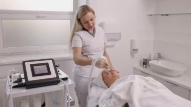 Süpürge kaldırma, kaldırma masajı, yüz gerdirme ameliyatı. Kadın kozmetik uzmanı hastaya cilt yenileme tedavisi uyguluyor. Bu da vakum kaldırma masajı ve kaldırma ameliyatını da kapsıyor..