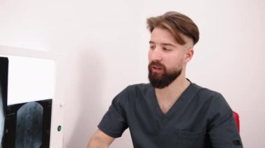Tıbbi Sonuçlar, Doktor Danışmanlık, Radyoloji İncelemesi. Genç sakallı doktor, tıbbi bulguları arka planda röntgen görüntüleri olan ışıklı kutuyla tartışıyor..