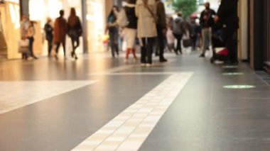 Kalabalık yürüyüşü, alışveriş merkezi, mağaza. Alışveriş torbalarıyla bacakları yakın çekim, seçici odak, modern alışveriş merkezinin modern zemininde bir sürü insanla yürüyen kalabalık.