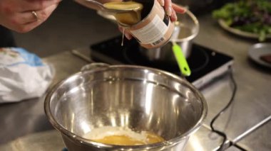 Süt, kase karıştırma, süt akışı. Yakın plan çekimde, yoğunlaştırılmış süt konserve kutusundan büyük paslanmaz çelik karıştırma kabına, pürüzsüz akışkan sıvıya dökülür..